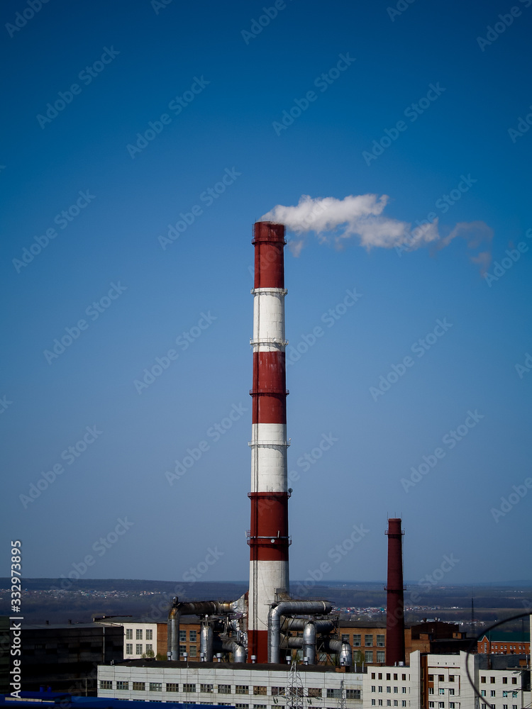 steam smoke coming from a chimney in an industrial zone on the outskirts of a city steam smoke coming from a chimney in an industrial zone on the outskirts of a city
