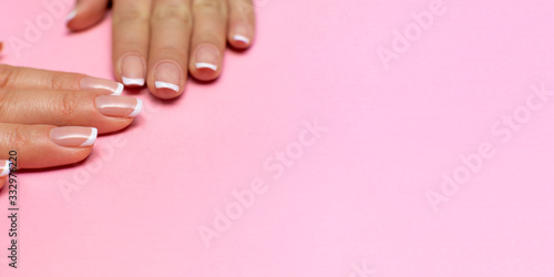 female fingers with a neutral transparent manicure on nails on a pink background. beauty salon. copy space. place for text or logo. high resolution widescreen image