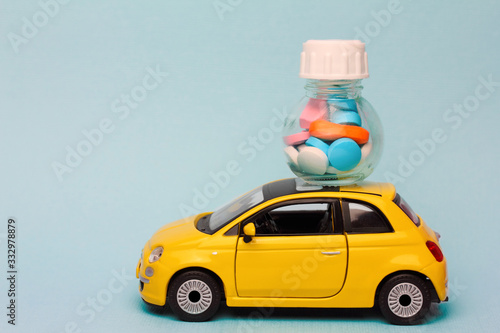 home delivery of medicines ordered via the Internet . a yellow toy car carries a bottle of pills on the roof. on a blue background