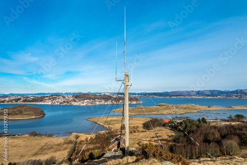Antenna post on top of a hill in Tananger suburb and scenic view of Hafsfjord fjord in a nice sunny spring day, Norway, March 2018 photo