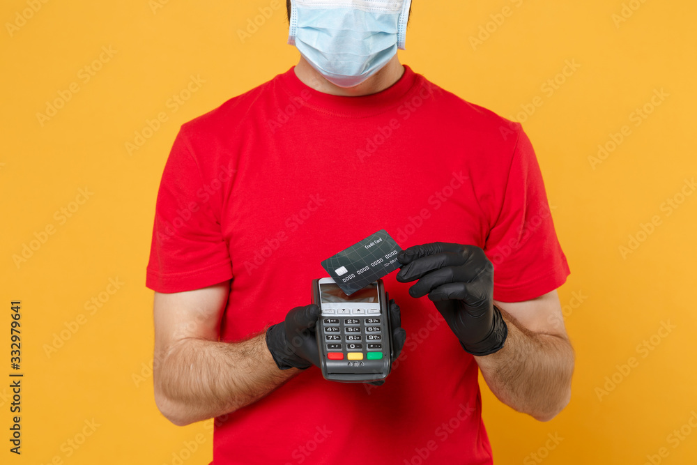 Delivery man in red cap blank t-shirt sterile mask gloves isolated on yellow background studio Guy employee hold bank payment terminal Service quarantine pandemic coronavirus virus 2019-ncov concept Delivery man in red cap blank t-shirt sterile mask gloves isolated on yellow background studio Guy employee hold bank payment terminal Service quarantine pandemic coronavirus virus 2019-ncov concept