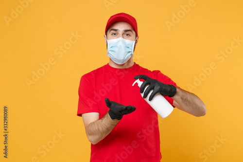 Delivery man employee in red cap t-shirt uniform sterile face mask glove hold bottle sanitizer soap isolated on yellow background studio Service quarantine pandemic coronavirus virus 2019-ncov concept