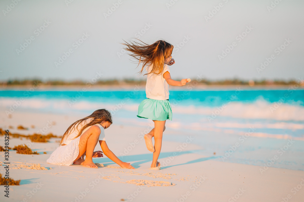 Naklejka premium Adorable little girls have a lot of fun on the beach.