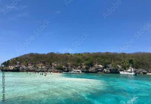 Scenic view over beach with boats and tourists, green and blue water, island in background, Cebu Island, Philippines