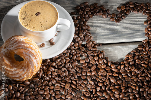 white cup with hot coffee on a background of coffee beans and hearts