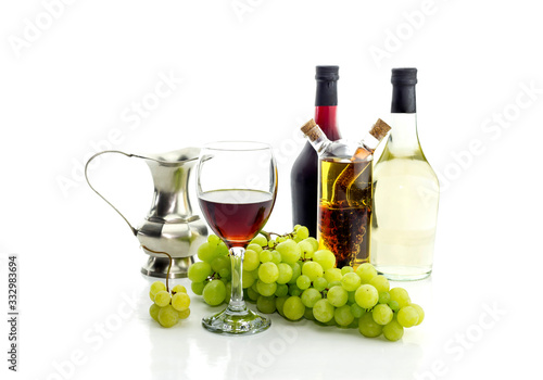 Bottles of wine, pitcher, wine glass and grapes on a white background close-up