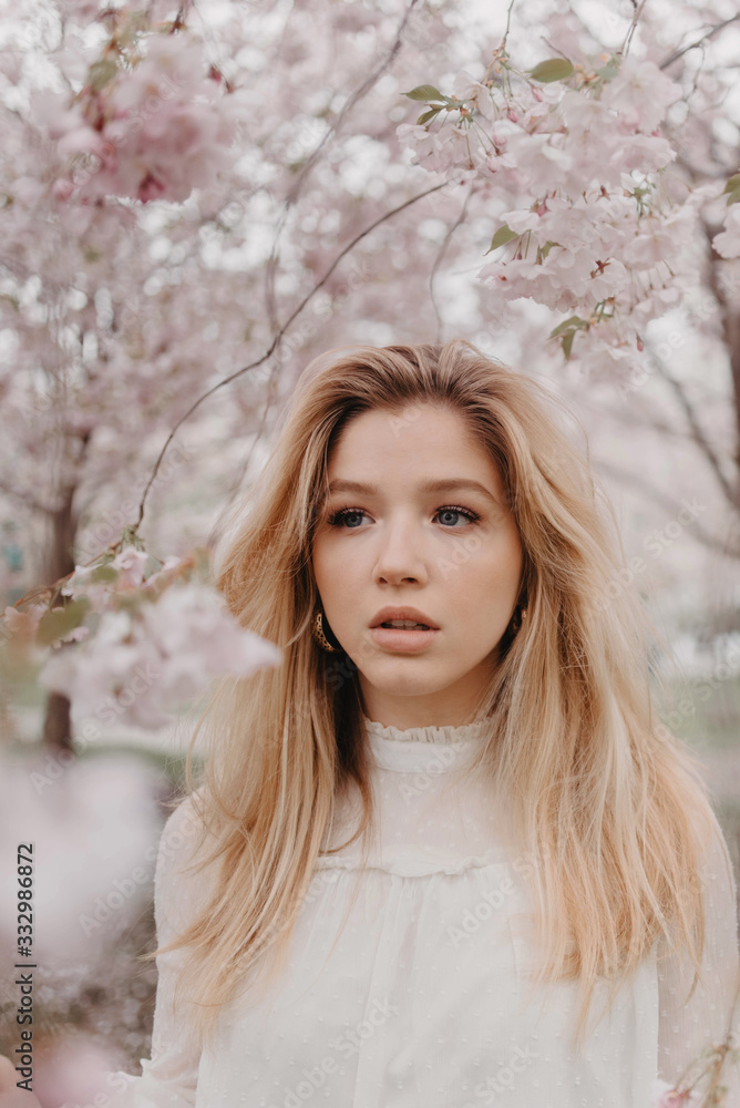 A young blonde woman standing amongst the cherry blossom trees A young blonde woman standing amongst the cherry blossom trees