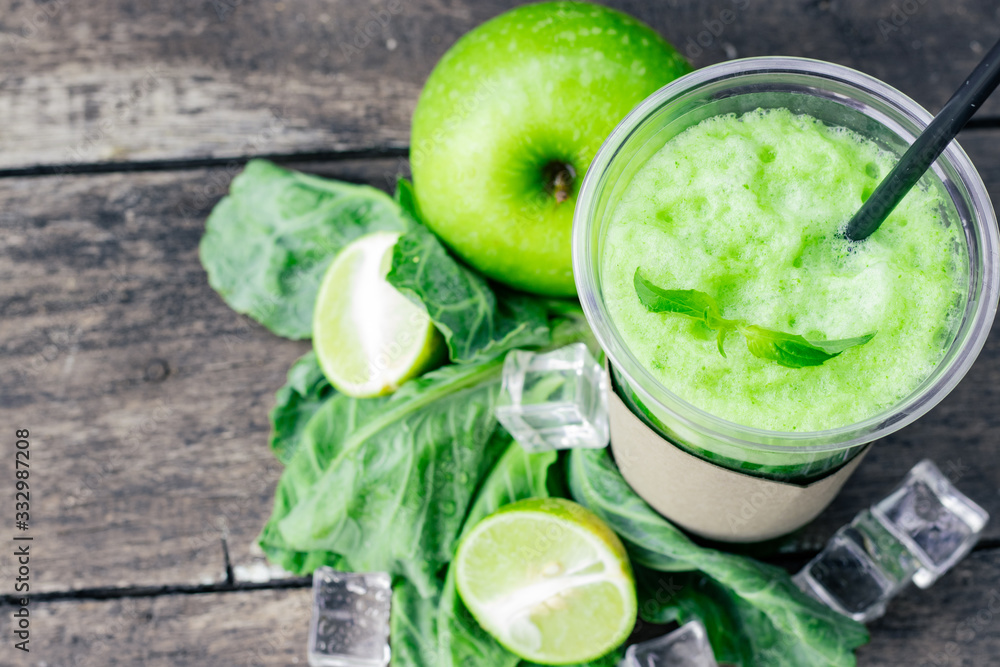 Green apple smoothie in glass and kale leaves on wooden table Green apple smoothie in glass and kale leaves on wooden table