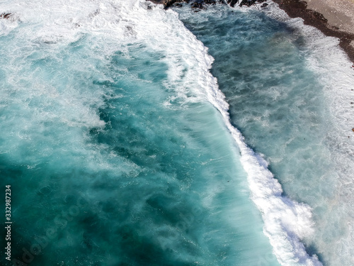 Aerial drone view of spashing waves in blue ocean