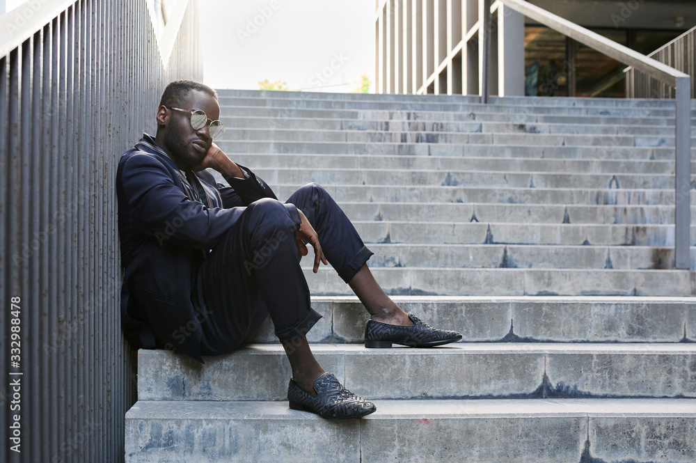 Pensive ethnic afro businessman sitting outdoors. Pensive ethnic afro businessman sitting outdoors.