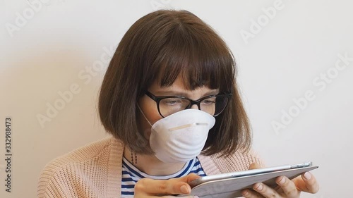 Caucasian young woman wearing face mask during Coronavirus pandemic quarantine using tablet
