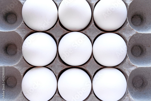White eggs in a package on a blue background close-up view from above. 