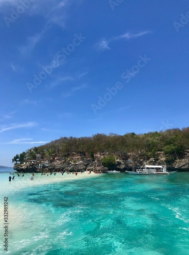 Scenic view over beach with boats and tourists, green and blue water, island in background, Cebu Island, Philippines © HWL Photos