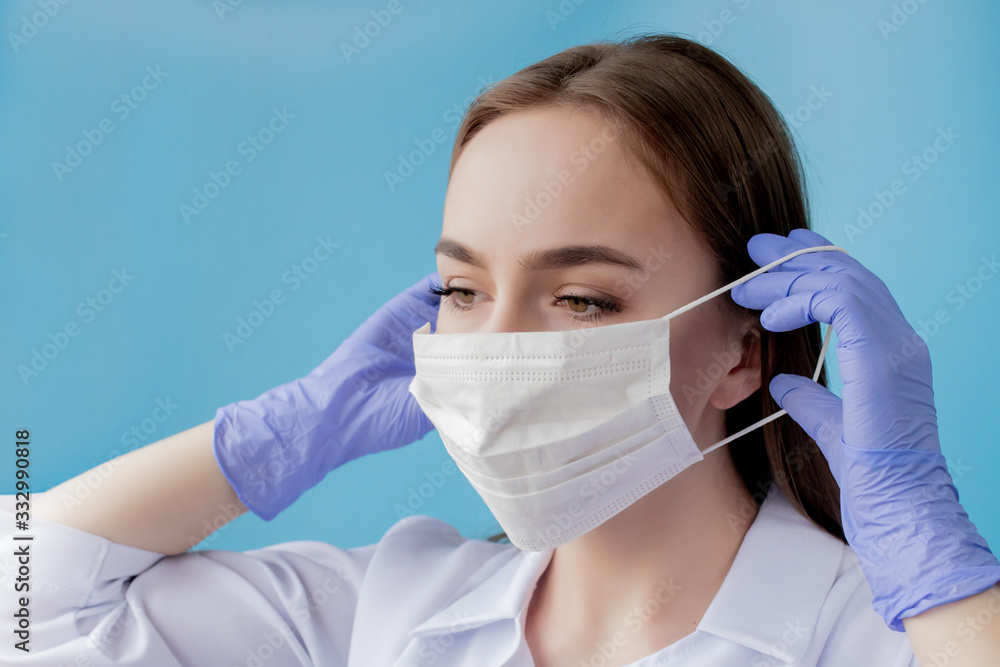 Doctor nurse smiling behind surgeon mask. Closeup portrait of young caucasian woman model on blue background. Woman wearing mass to protect covid-19 Doctor nurse smiling behind surgeon mask. Closeup portrait of young caucasian woman model on blue background. Woman wearing mass to protect covid-19