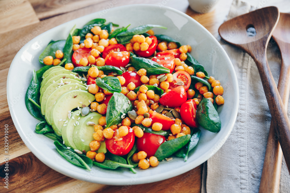 Fresh healthy salad with chickpea, avocado, cherry tomatoes and spinach.