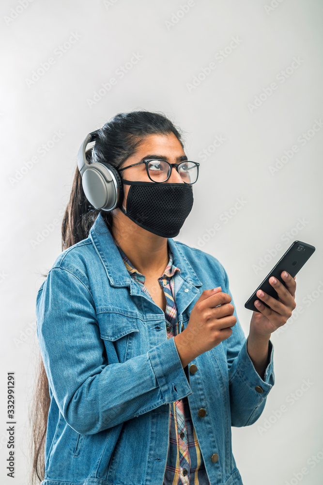A teenager girl with mask enjoying music while quarantine during covid-19 pandemic