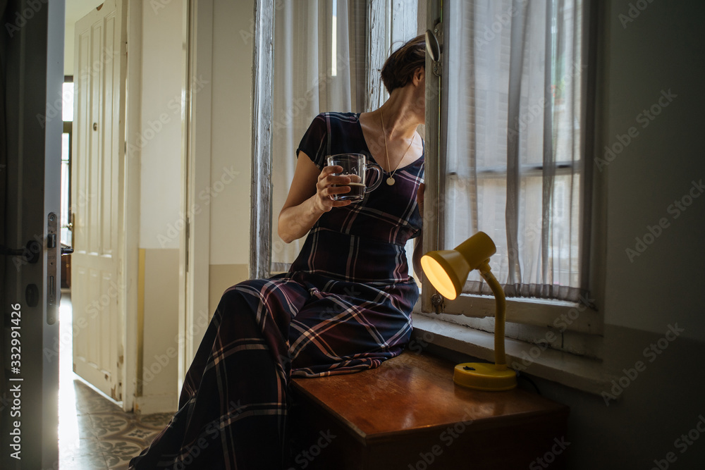 Anonymous female with mug looking out window Anonymous female with mug looking out window
