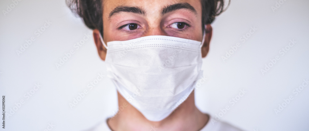 close up of one boy alone at home or hospital wearing medical mask to prevent any type of illness or virus or disease like coronavirus or covid-19 - sick young man with a disease infected close up of one boy alone at home or hospital wearing medical mask to prevent any type of illness or virus or disease like coronavirus or covid-19 - sick young man with a disease infected