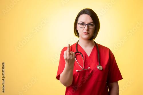 Beautiful woman doctor with stethoscope, wearing red scrubs showing fuck you