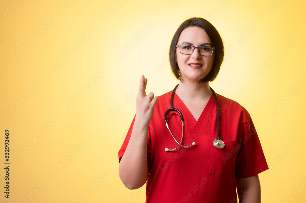 Beautiful woman doctor with stethoscope, wearing red scrubs showing good luck Beautiful woman doctor with stethoscope, wearing red scrubs showing good luck