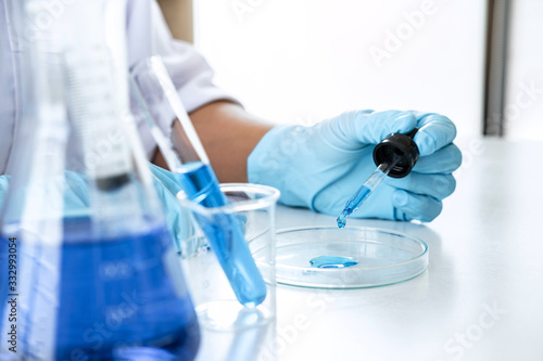 Biochemistry laboratory research  Scientist or medical in lab coat holding test tube with using reagent with drop of color liquid over glass equipment working at the laboratory