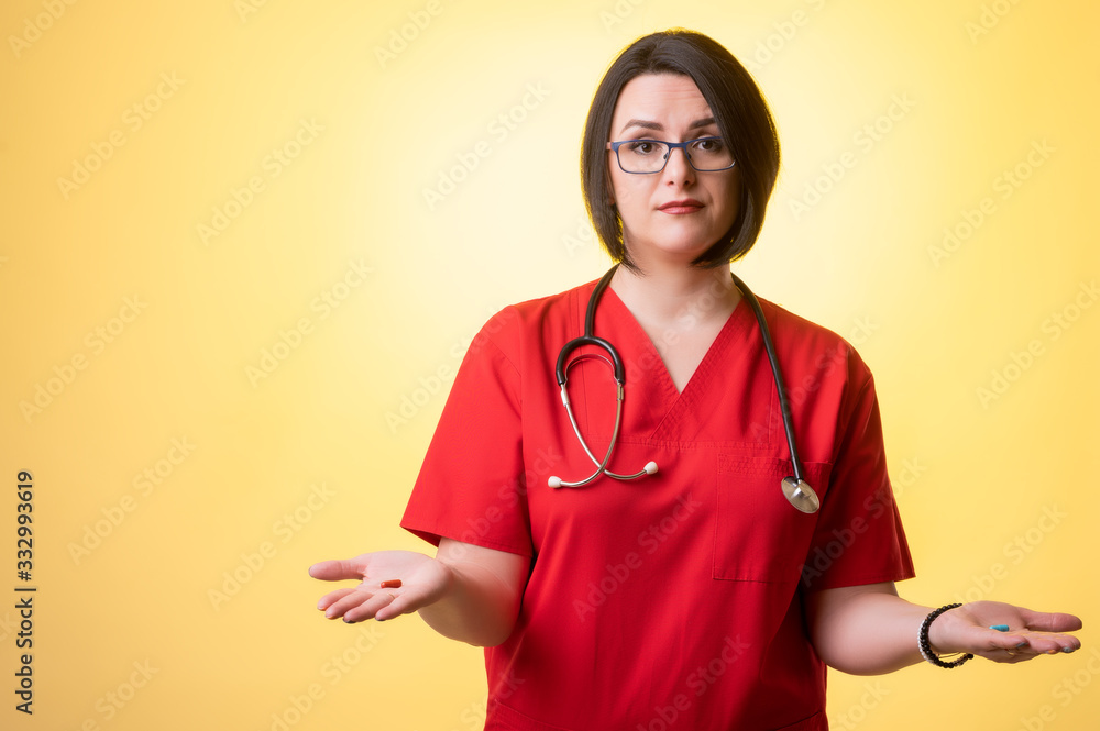 Beautiful woman doctor with stethoscope, wearing red scrubs showing red and blue pills on hands, in doubt Beautiful woman doctor with stethoscope, wearing red scrubs showing red and blue pills on hands, in doubt