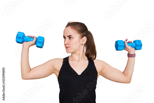 young woman performs an exercise with dumbbells looking to the side, isolated on white background