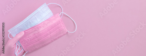 Pink protective surgical face mask and woman hands in gloves background, selective focus, banner