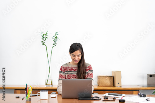 Young freelancer working from a makeshift home office connected to the internet with a laptop and a phone during the period of global confinement