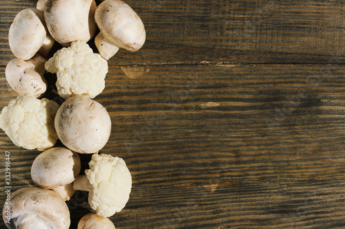 Cauliflower and champignons on a brown wooden background. Healthy food, vegetables concept.