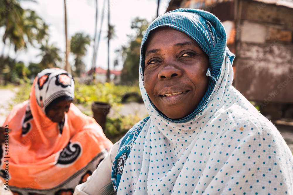 coexistence of two zanzibari women. One is smiling and the other is in the background coexistence of two zanzibari women. One is smiling and the other is in the background