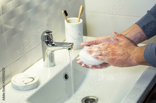 A man use soap and washing hands under the water tap. Hygiene concept hand detail