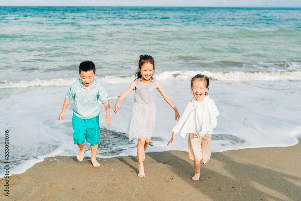 Children running and laughing together on the beach Children running and laughing together on the beach