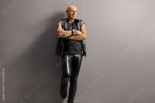 Middle aged punk man leaning on a gray wall