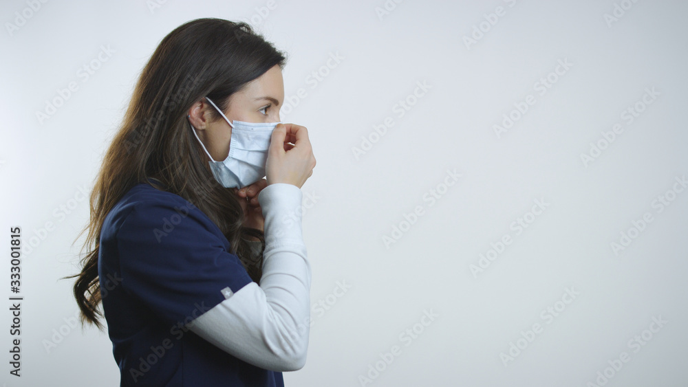 Profile view of brunette nurse showing how to correctly wear breathing mask Profile view of brunette nurse showing how to correctly wear breathing mask