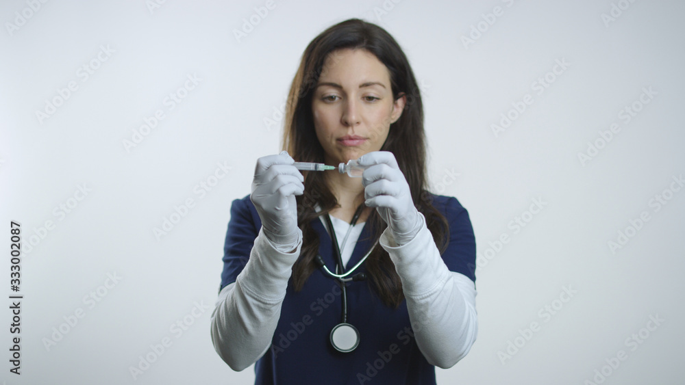 Nurse begins to draw medication from vial using needle and syringe Nurse begins to draw medication from vial using needle and syringe
