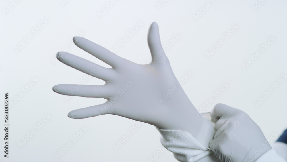 Close up of latex glove being pulled over hand by female nurse