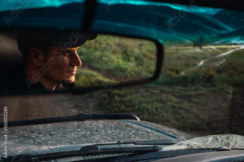 Reflection of man in car rear view mirror