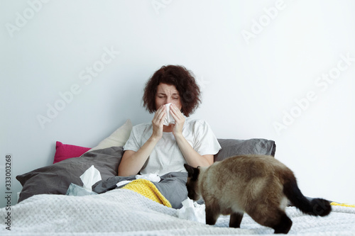 Woman sneezing near cat