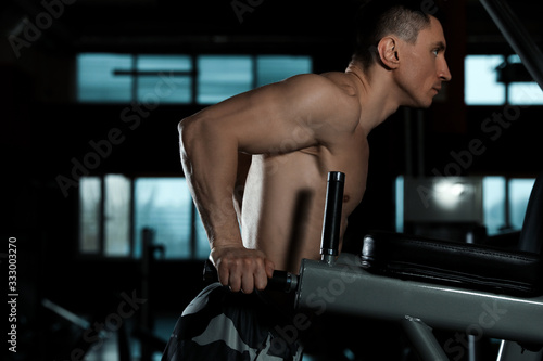 Strong man working out on parallel bars in modern gym
