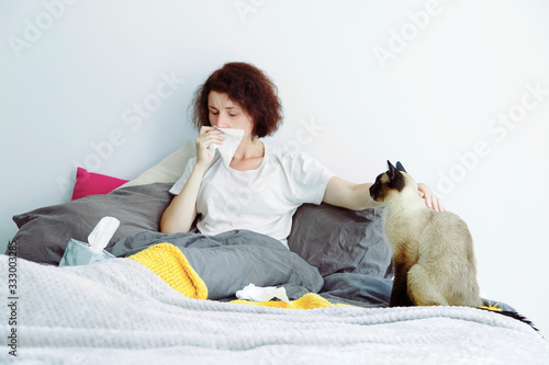 Ill female stroking cat and sneezing photo