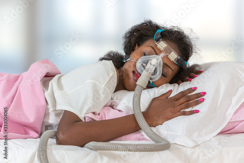 Woman wearing CPAP headgear to sleep against apnea photo