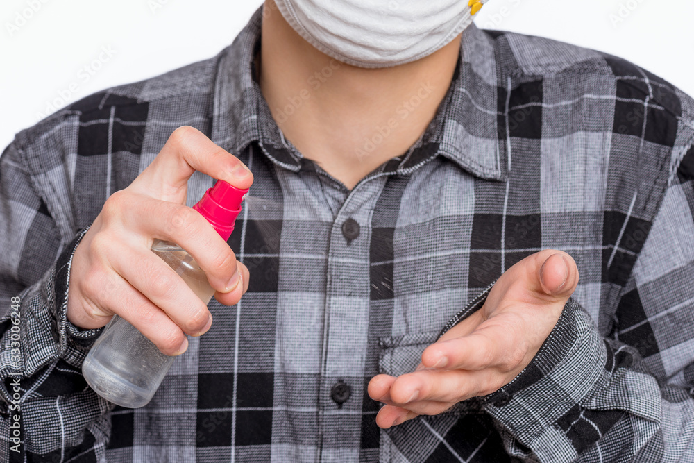 Fototapeta premium Concept of coronavirus quarantine. Child wearing medical protective mask applying an antibacterial antiseptic spray for hands disinfection and health protection during flu virus outbreak. COVID-19.
