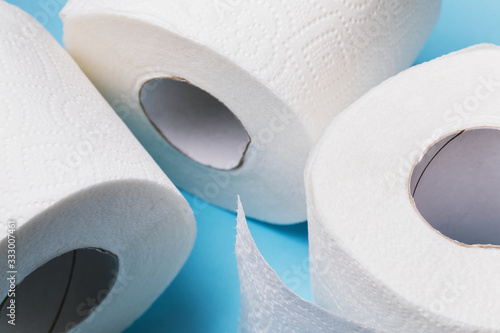 Three rolls of toilet paper on a blue background, close-up