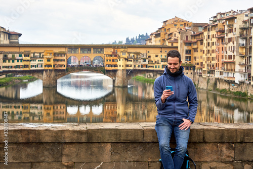 Man using his phone In Front Of Ponte Vecchio. Florence Tuscany Italy photo