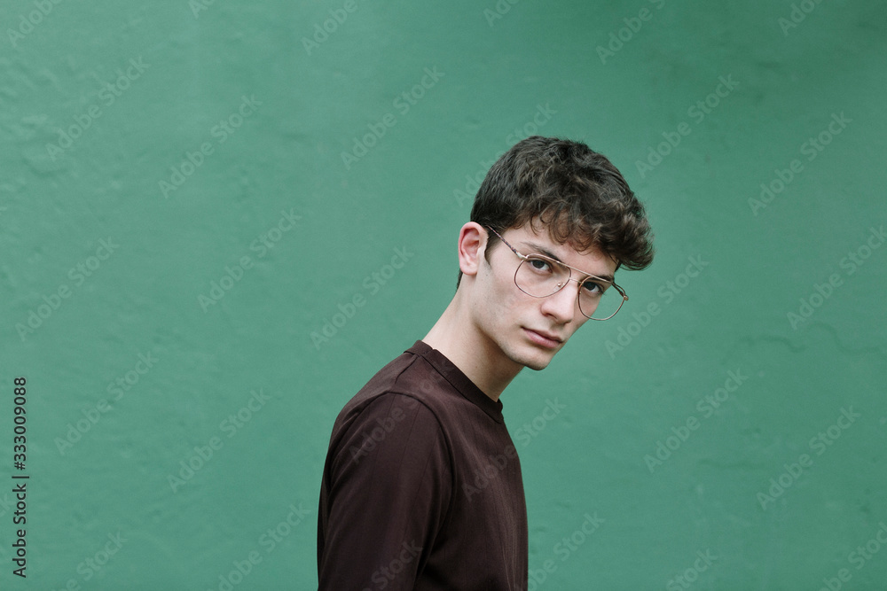 Serious young man looking at camera on green background Serious young man looking at camera on green background