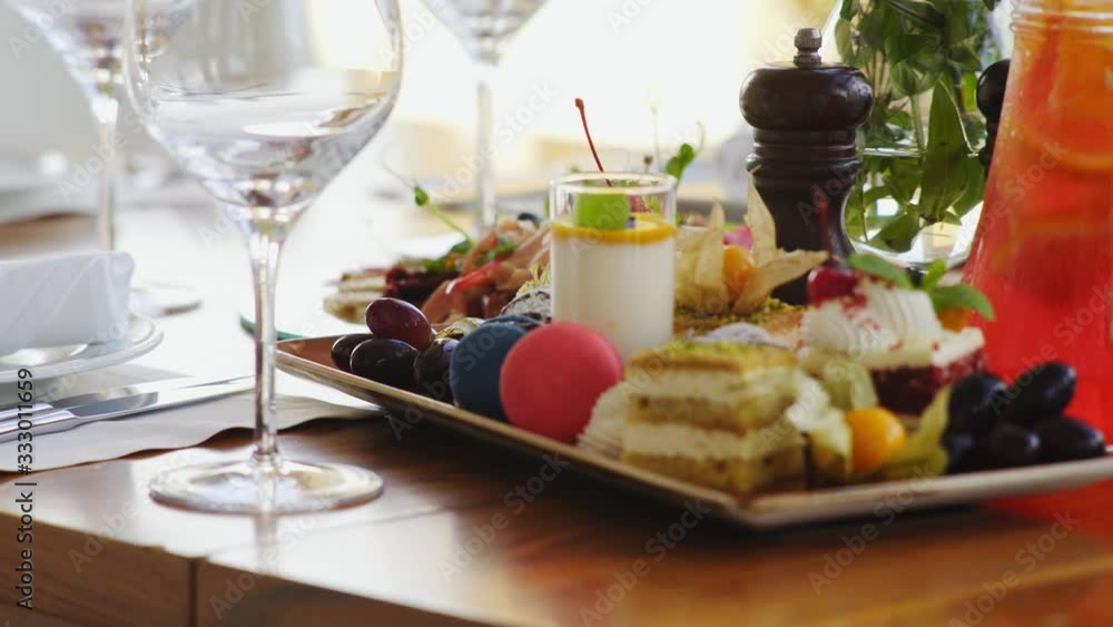 Dinner table served with delicious dishes and beverage. Luxury restaurant interior, lateral motion shot empty clear vine glass and plates full of food on wooden desk, detail view Dinner table served with delicious dishes and beverage. Luxury restaurant interior, lateral motion shot empty clear vine glass and plates full of food on wooden desk, detail view