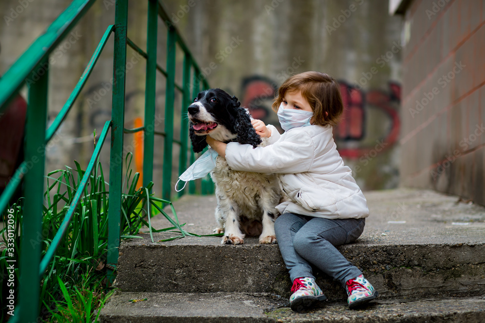 a girl in a medical mask, walking on the street with a dog