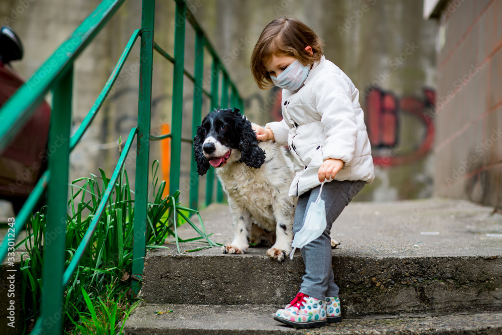 a girl in a medical mask, walking on the street with a dog