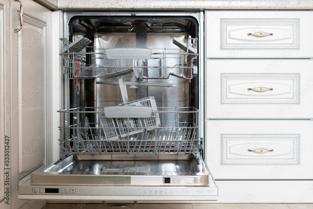 opened new empty dishwasher machine in the kitchen opened new empty dishwasher machine in the kitchen